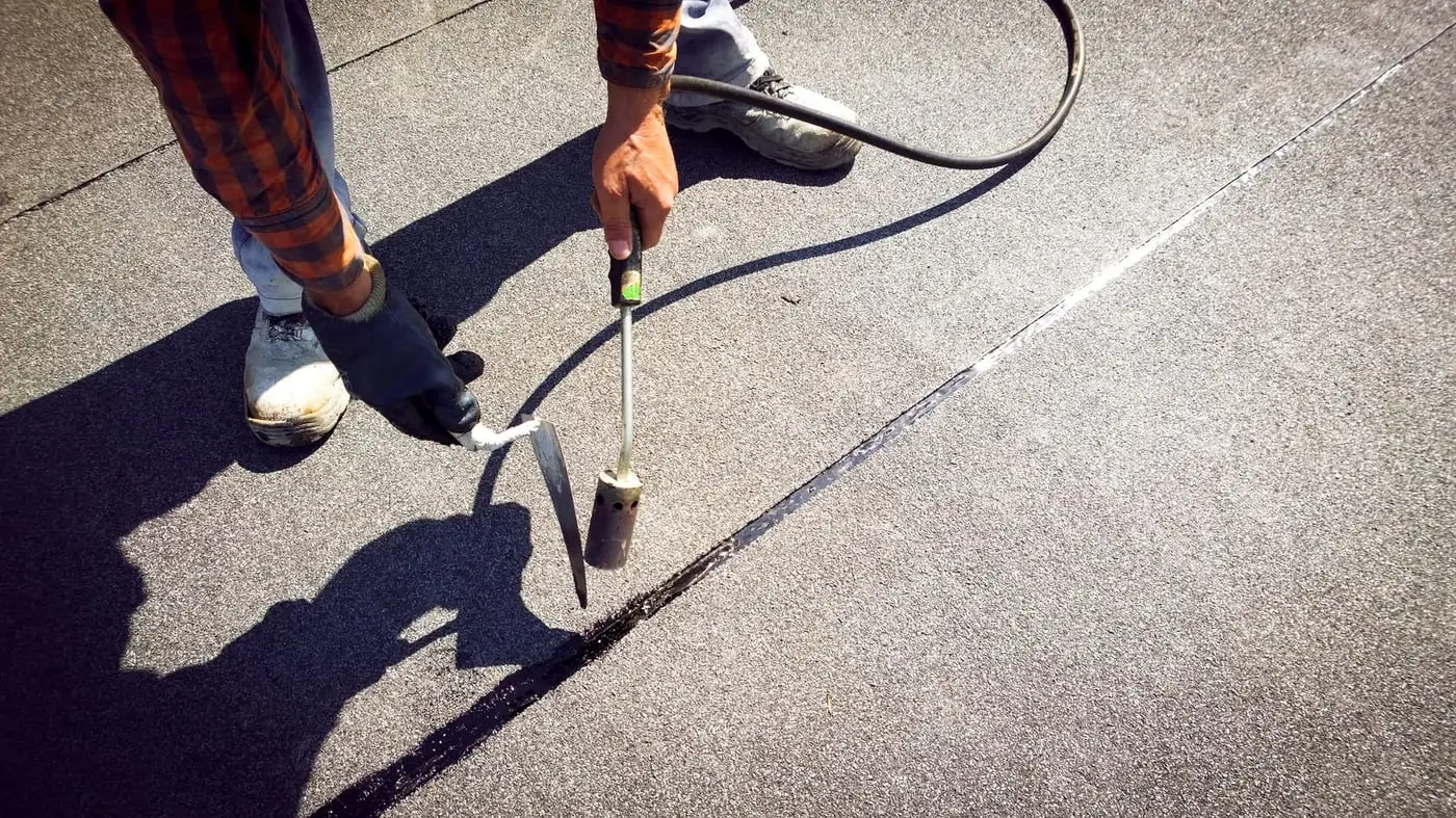 Roofer sealing a joint on a flat roof during waterproofing works