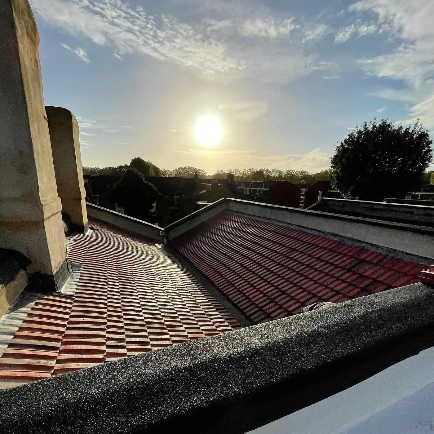 Tiled London rooftop with parapet and valley detailing at sunset